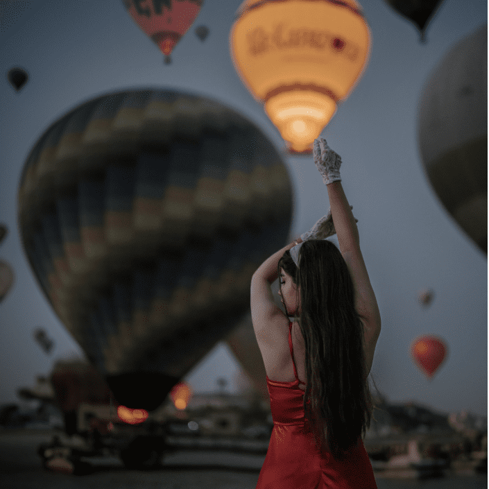 a woman are taking a picture in front of balloons in Cappadocia