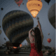 a woman are taking a picture in front of balloons in Cappadocia